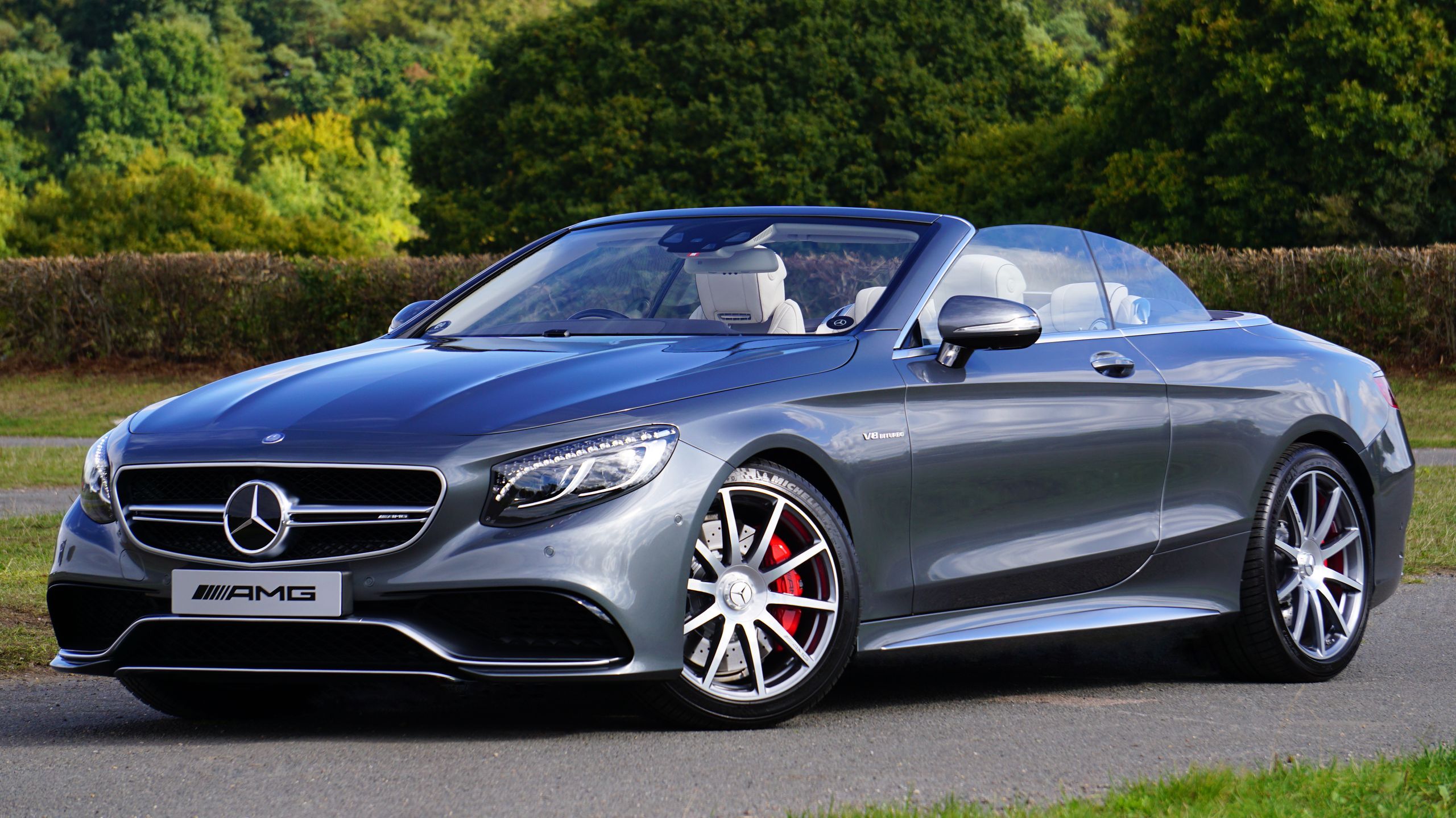 A sleek, gray luxury convertible car resting in a scenic outdoor park area, epitomizing style and design.